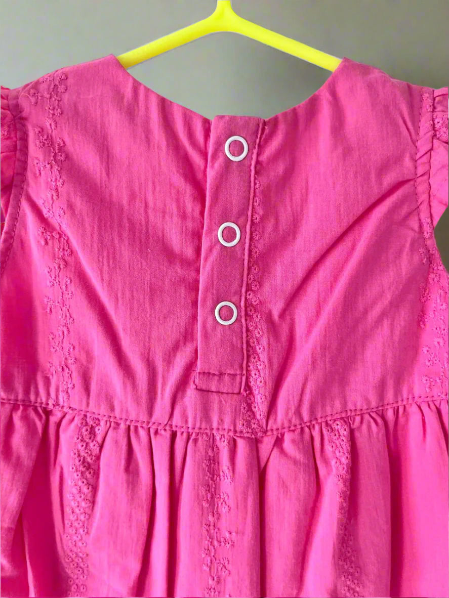 Pink dress with lace details on a yellow hanger against a white background