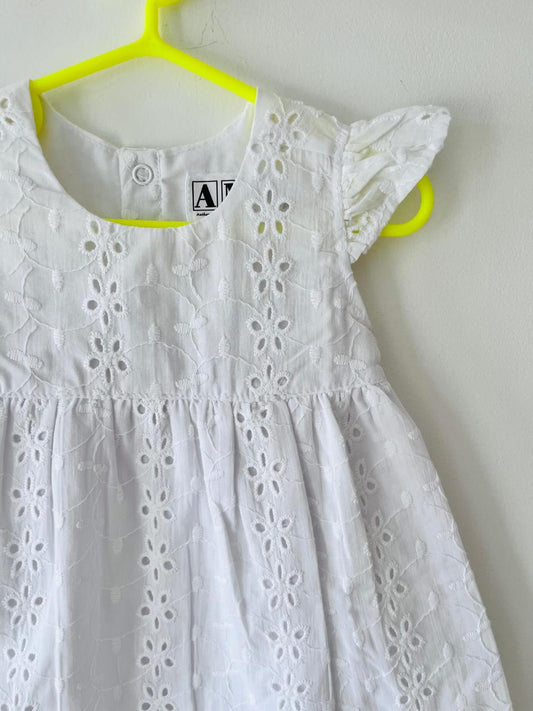 White dress with lace details on a yellow hanger against a white background