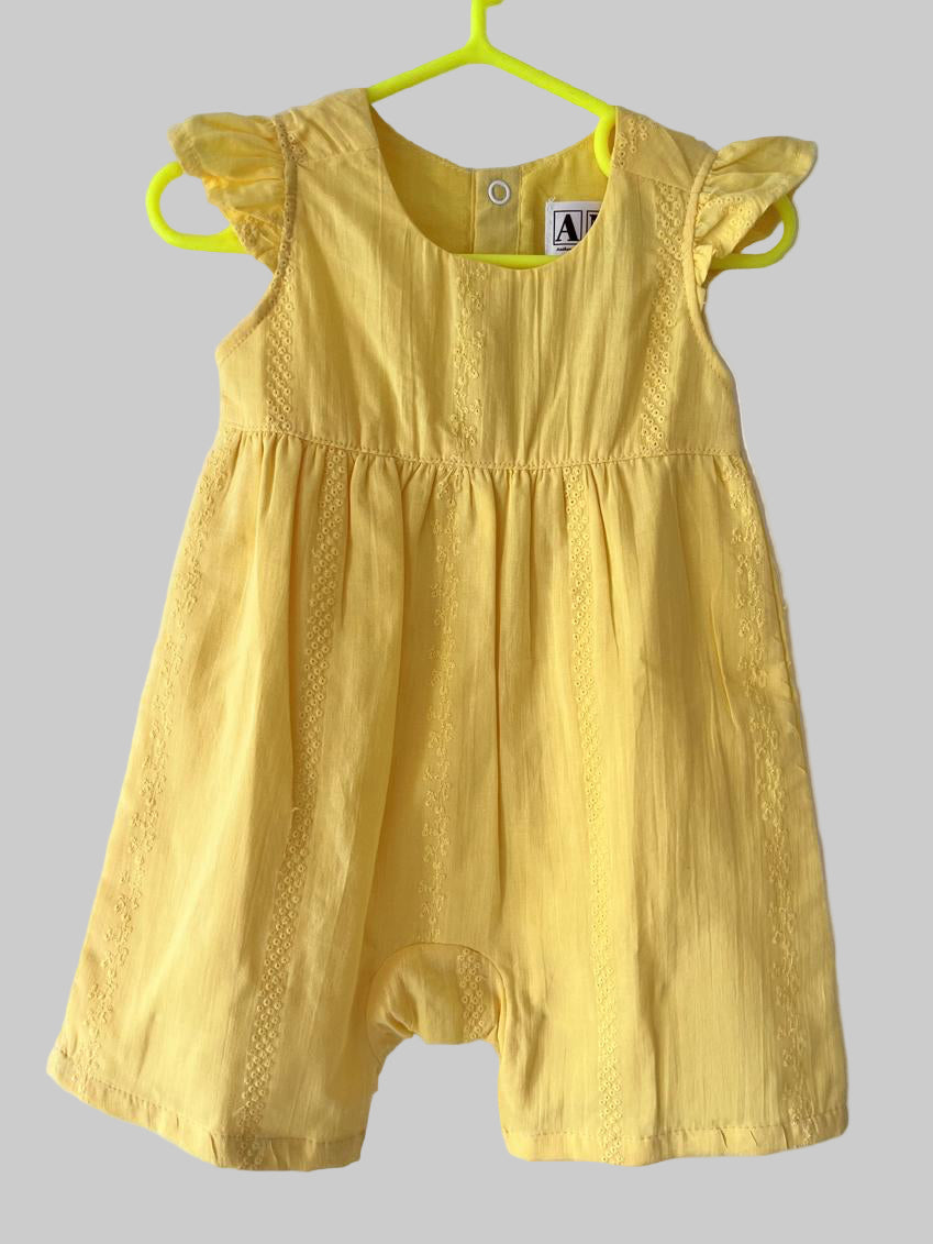 Yellow baby romper on a hanger against a white background